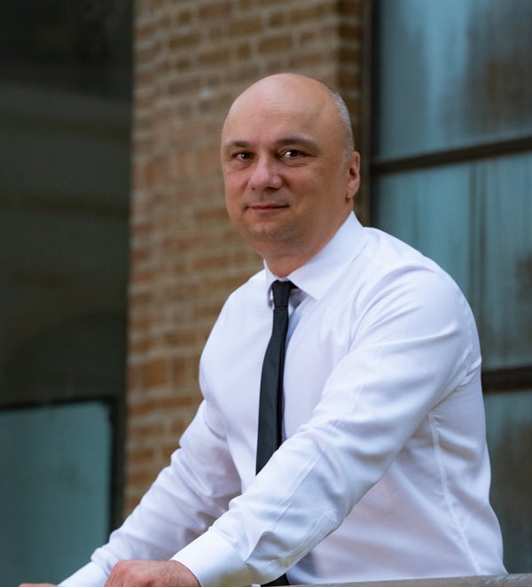 Rice School of Architecture Dean Igor Marjanović leans over a railing outside of MD Anderson Hall.